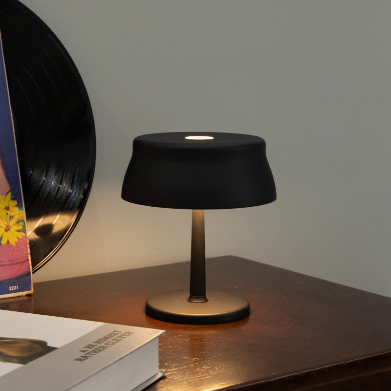 Luna Mini opladelig bordlampe i sort med varmt hyggelys på mørkt træbord i moderne hjem